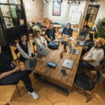 A group of diverse professionals collaborating in a modern office setting with laptops and technology.