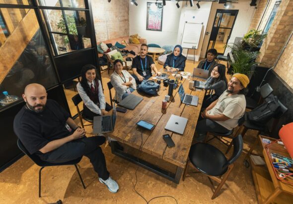 A group of diverse professionals collaborating in a modern office setting with laptops and technology.