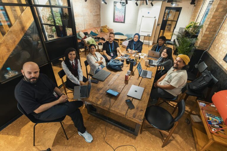 A group of diverse professionals collaborating in a modern office setting with laptops and technology.