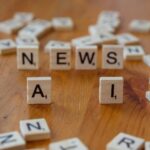 Wooden Scrabble tiles spelling 'AI' and 'NEWS' for a tech concept image.